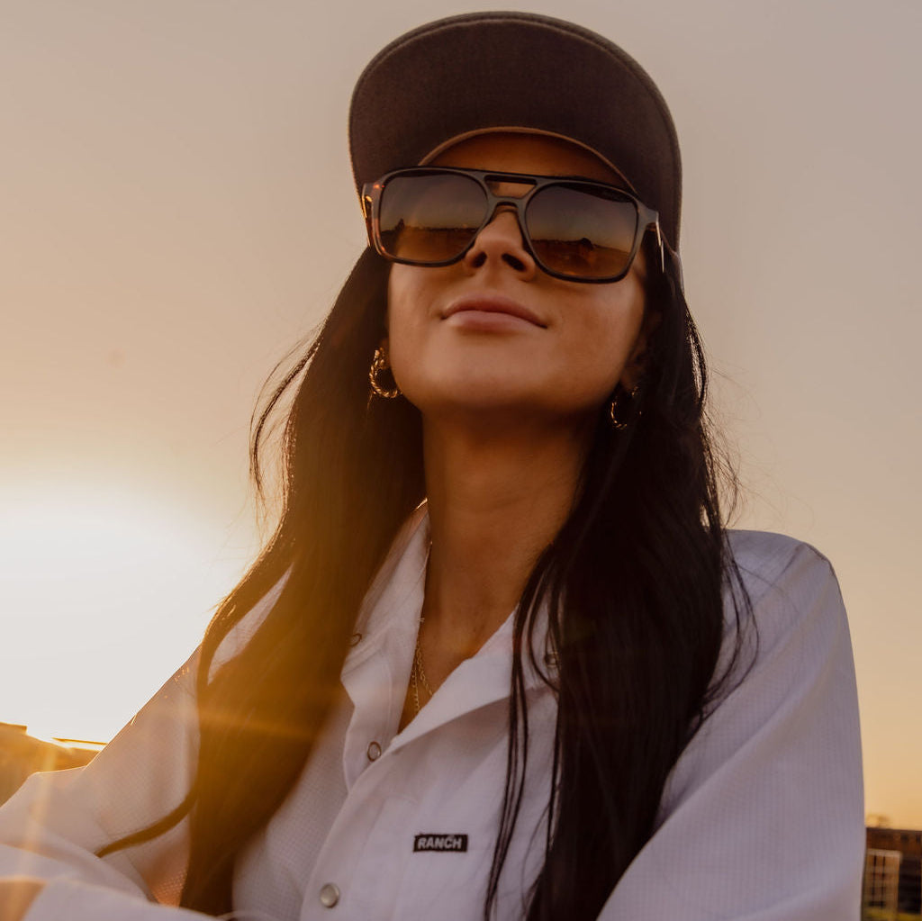 Woman wearing a cap and sunglasses with a blurred background